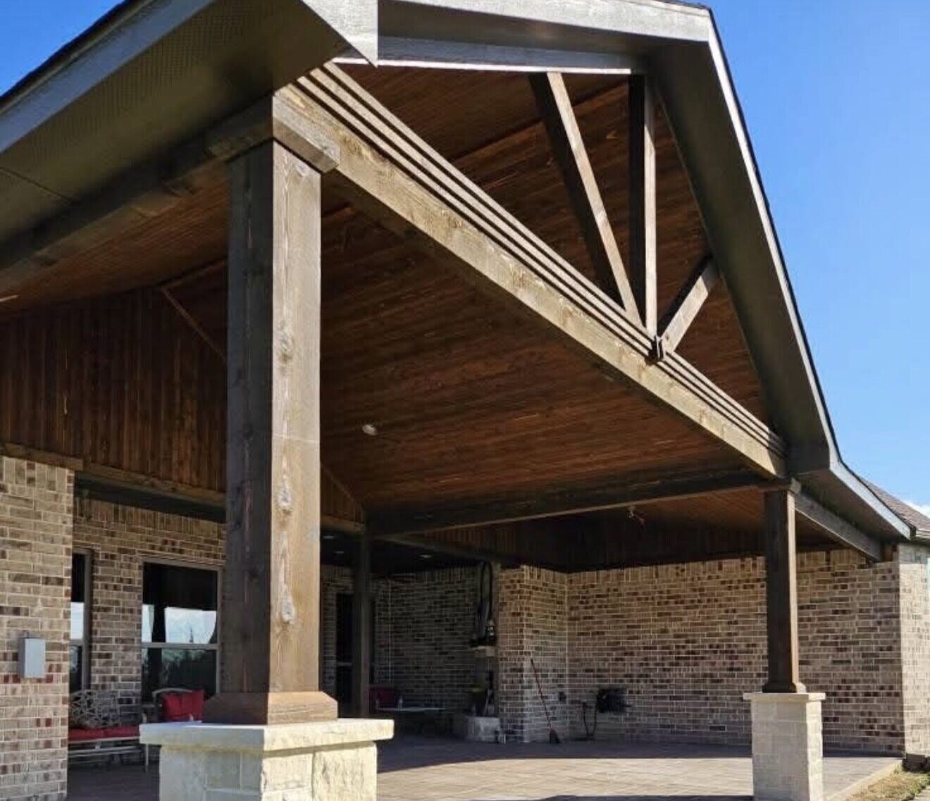 Custom covered patio with exposed wood beams and stone columns in the DFW area